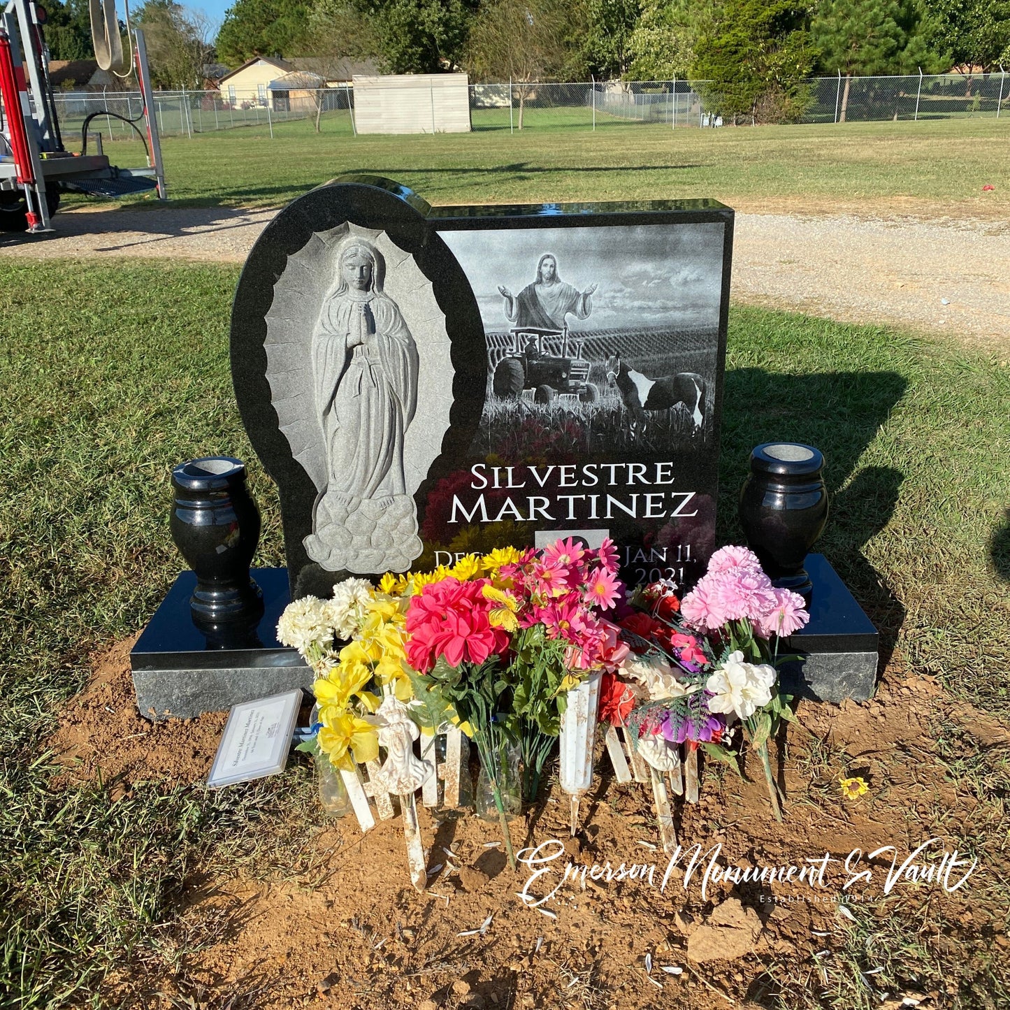 Photo of Emerson Monument Company's Black Granite Memorial Headstone personalized and in the graveyard for Silvestre Martinez. WIth Flowers.